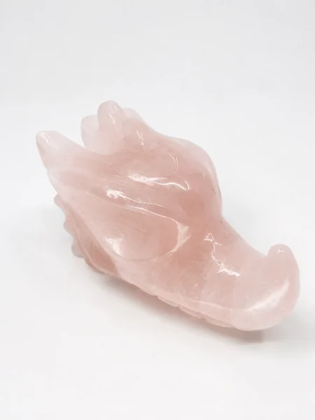 Side view of polished Rose Quartz dragon head carving showing detailed horns and sculpted features